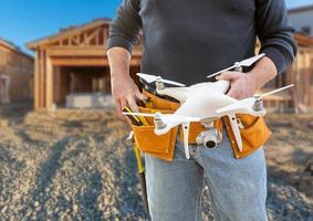 trabajador de la construcción y piloto de drones con cinturón de herramientas sosteniendo drones en el sitio de construcción foto