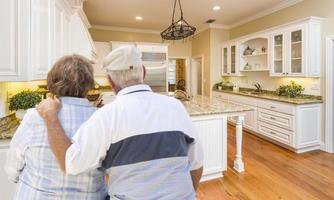 Senior Couple Looking Over Beautiful Custom Kitchen photo