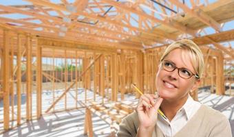 Pensive Woman with Pencil On Site Inside New Home Construction Framing. photo