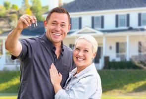 Young Adult Couple With House Keys In Front of Beautiful Home photo