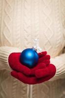 mujer con mitones rojos de temporada sosteniendo adornos navideños azules foto
