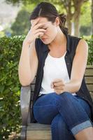 Upset Young Woman Sitting Alone on Bench photo