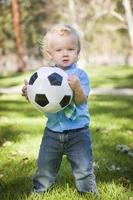 chico lindo joven jugando con una pelota de fútbol en el parque foto