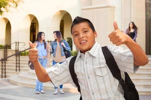 joven estudiante hispano masculino con los pulgares hacia arriba en el campus foto