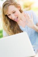 mujer adulta joven en vivo chateando en video al aire libre usando su computadora portátil. foto