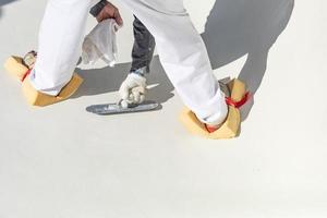 Worker Wearing Sponges On Shoes Smoothing Wet Pool Plaster With Trowel photo