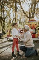 Grandfather having fun with his little granddaughter in the amusement park photo