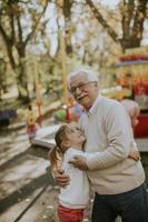 abuelo divirtiéndose con su nieta en el parque de atracciones foto