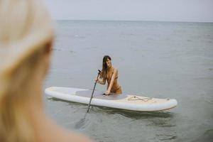 Two young women with paddle board in the sea on a summer day photo