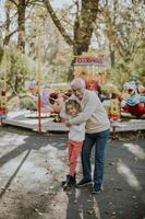 abuelo divirtiéndose con su nieta en el parque de atracciones foto