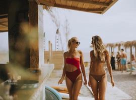 Young women in bikini walking by the surf cabin on a beach at summer day photo