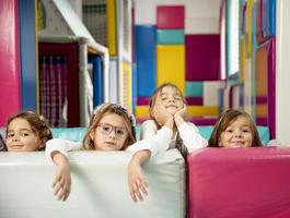 Group of cute little girls hiding behind large leather blocks photo