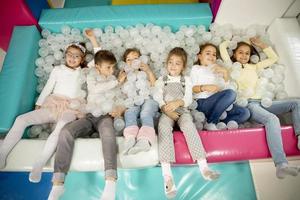 Happy little kids in ball pit smiling happily at camera while having fun photo