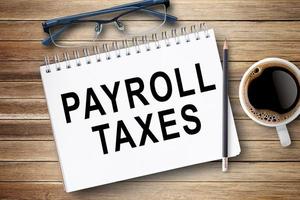 PAYROLL TAXES,Text on notebook in office desk workplace background.