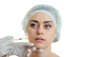 a young girl in a special medical doctor Hat makes injection on face photo