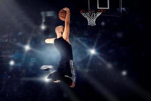 Basketball player jumping to the ring and makes slam dunk photo