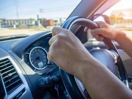 A man's hand held the steering wheel of a car to steer while the car was moving away. Concept and direction of business operations according to the plan. Direction control concept. photo