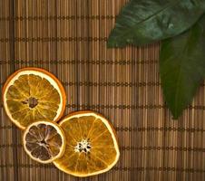 Dried orange slices and leaves on a bamboo mat. photo