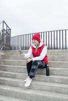 Woman wearing knee brace or orthosis after leg surgery, sitting on stairs ourdoors photo