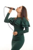 Charming young girl in green dress singing a karaoke photo