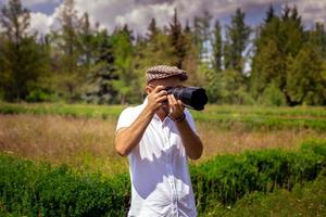 hombre fotógrafo toma fotos en cámara en el parque verde