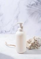 A minimalistic scene of a podium and white dispenser bottle with stones on white background, for natural cosmetics photo