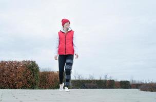 Woman wearing knee brace or orthosis after leg surgery walking in the park photo