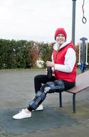 Woman wearing knee brace or orthosis after leg surgery working out in the park photo