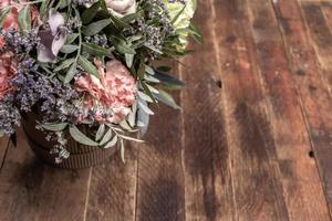 Retro wooden backdrop with flowers bouquet in diy cardboards vase close up with copy space. photo