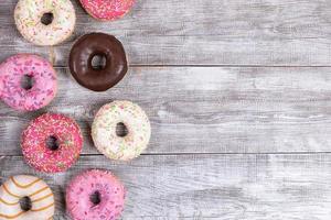 Traditional doughnuts with multicolored glaze laid out on white painted wooden table. Top view, copy space. photo