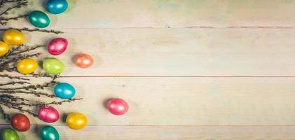 Easter festive banner with soft focus with colored Easter eggs and willow twigs on painted wooden background. photo