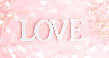 letras blancas amor con marco de gipsofila blanca suave en rosa pastel con corazones de luces bokeh. foto