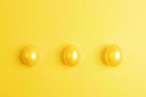 Three glossy painted yellow Easter eggs are lying in row on yellow background. Top view. photo