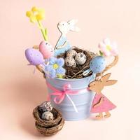 idea de decoración para niños de pascua: cubo pequeño, nidos de huevos de codorniz, huevos decorativos, flores, conejitos. foto