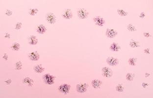 Creative floral background with flowers of lilac laid out in circle with copy space inside it on trendy pink backdrop. photo