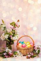 Easter composition of basket of painted Easter eggs, Apple tree twigs with background with hexagonal bokeh. Vertical. photo