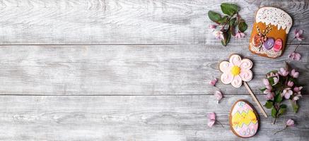 Easter banner. Festive decor Pink Apple tree flowers, gingerbreads as Easter cake, flower and egg on wooden background. photo