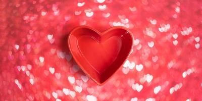 Close-up three red roses in red vase shaped heart on pink bokeh background with hearts. photo