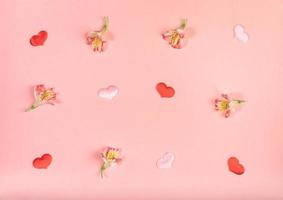Valentines day background of flowers Alstroemeria and small textile hearts on pink. Top view, flat lay, knolling. photo