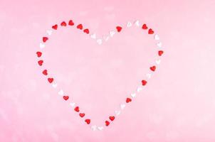 Valentines day festive background or greeting card. Small textile white and red hearts laid out in shape of heart. photo