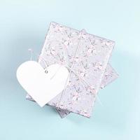 Gift boxes wrapped with grey paper with floral pattern and white paper heart on light blue. Valentine's day mockup. photo