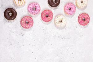 Top view to doughnuts with multicolored glaze laid out on concrete background with copy space. photo