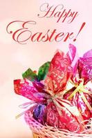 Easter card - eggs wrapped in color paper close up on pink, words Happy Easter and bokeh lights. photo