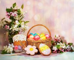 Easter composition of basket of painted Easter eggs, painted gingerbreads, Apple tree twigs with backdrop with bokeh. photo