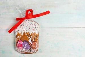 One gingerbread Easter cake packed in cellophane as festive gift on wooden backdrop. Traditional Easter symbol. photo