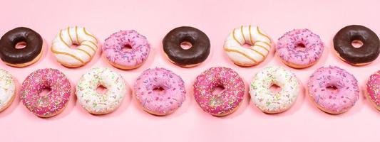 Doughnuts with multicolored glaze laid out in two rows on trendy pink background. Creative web banner. photo