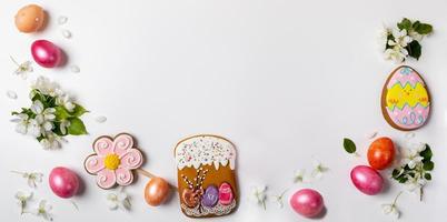 pancarta festiva de pascua. arreglo como arco de panes de jengibre, huevos de colores y ramitas de manzano blanco sobre fondo blanco. foto