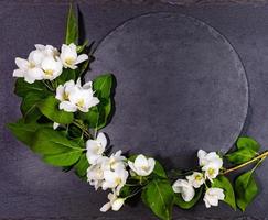 Empty shale round black serving board with white apple tree twig. Festive mockup for serving on spring holidays. photo