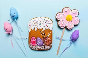 Gingerbread Easter cake and flower, decorative Easter eggs on sticks on light blue background. Easter festive backdrop. photo