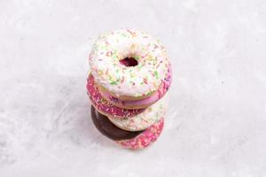 vista superior a la pila de seis donuts con glaseado multicolor en el centro de un fondo de hormigón borroso. enfoque selectivo. foto